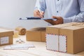 Courier making notes in delivery receipt among parcels at table Royalty Free Stock Photo