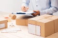 Courier making notes in delivery receipt among parcels at table Royalty Free Stock Photo