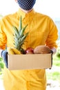 Courier man delivery box with exotic fruits food, contactless delivery. Service quarantine pandemic coronavirus.