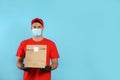 Courier in medical mask holding paper bag with takeaway food on light blue background, space for text. Delivery service during Royalty Free Stock Photo