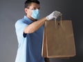 Courier in protective mask and medical gloves delivers takeaway food during coronavirus