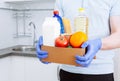 Courier in protective medical gloves delivers box with set food stock for quarantine isolation period. Online food store and Royalty Free Stock Photo