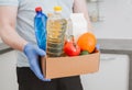 Courier in protective medical gloves delivers box with set food stock for quarantine isolation period. Organic food and products Royalty Free Stock Photo