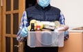Courier in protective medical mask and gloves deliver products in plastic box