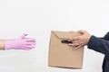 Courier in protective pink gloves hands over a food box to a client. Quarantine. Social distancing. Virus protection