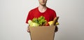 Courier in red uniform carrying package box of fresh grocery food from market. Delivery concept. Royalty Free Stock Photo