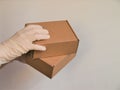 Courier`s hands in latex white medical gloves deliver parcels in brown cardboard boxes to the door during the epidemic of