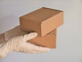 Courier`s hands in latex white medical gloves deliver parcels in brown cardboard boxes to the door during the epidemic of