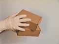 Courier`s hands in latex white medical gloves deliver parcels in brown cardboard boxes to the door during the epidemic of