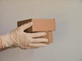 Courier`s hands in latex white medical gloves deliver parcels in brown cardboard boxes to the door during the epidemic of