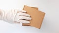 Courier`s hands in latex white medical gloves deliver parcels in brown cardboard boxes to the door during the epidemic of