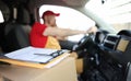 Courier in uniform in car and receipt documents on clipboard for client Royalty Free Stock Photo