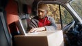 Courier using laptop in the van to confirm delivery address