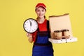 Courier woman holding wall clock and coffee with pizza box, express delivery in time. Royalty Free Stock Photo