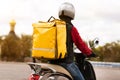 Courier With Yellow Backpack Delivering Meals On Scooter Outside, Rear-View