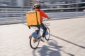 Courier with yellow backpack driving bike and coming to the client with parsels
