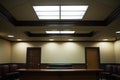 a courtroom witness box empty under ceiling lights