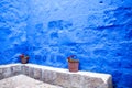 Courtyard with blue walls, indigo, along the wall two pots with geraniums.