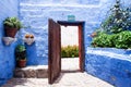 Courtyard with blue walls, an open wooden door in the center, flower pots along the walls, monastery Santa Catalina Royalty Free Stock Photo