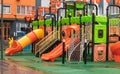 A courtyard of high-rise buildings with a new modern colorful and large playground on a rainy summer day without people. Empty Royalty Free Stock Photo