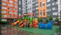 A courtyard of high-rise buildings with a new modern colorful and large playground on a rainy summer day without people. Empty Royalty Free Stock Photo