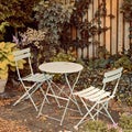 Courtyard metal chairs and table in a serene, peaceful, lush, private backyard at home in autumn. Patio furniture set in Royalty Free Stock Photo