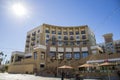 A courtyard with shops and apartments and people sitting at tables with umbrellas with a clear blue sky in Pasadena California