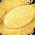 Couscous grains in wooden spoon closeup