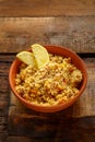 Couscous masfouf with dried fruits and nuts in a clay plate on a board on a wooden table.