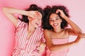 Cousins in wonderful mood are lying on floor in high spirits. Girls pose with sincere smiles in pin Royalty Free Stock Photo