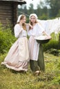 Coutryside Lifestyle. Portrait of Two Lovely Country Girls Posing Together With Basin Outdoor With Linens Sheets Hanged On Rope Royalty Free Stock Photo
