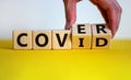 Cover covid. Male hand turns cubes with words `cover covid`. Covid-19 postpandemic concept. Beautiful yellow table, white Royalty Free Stock Photo