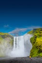 Cover page with famous Skogafoss waterfall with a lonely standing person in orange jacket, while hiking in Iceland, summer, scenic Royalty Free Stock Photo