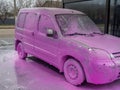 Covered auto with pink foam at a self-service car wash