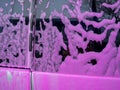 Covered auto with pink foam at a self-service car wash