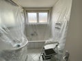 Covered bathroom walls with tarp and ladder in preparation for painting