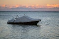 Covered boat docked at the pier by the shore at sunset. Covered yacht on the water with colourful sunset sky in the background Royalty Free Stock Photo