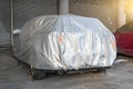 Covered car on a yard in front of the garage door. Car Cover Carport Parking