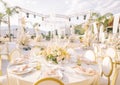 Covered festive tables with bouquets of flowers and candles stand on the open air terrace