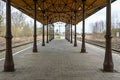 Covered platform with vintage columns, metal scaffolding and wooden roof between the railroad tracks on the station in Schonberg,