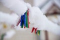 Covered with snow colorful clothespins on the line, close-up Royalty Free Stock Photo