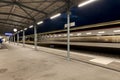 Covered station platform illuminated by led lights. The train passes by at full speed