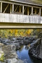 Covered wooden bridge over a rocky ravine with a mountain stream and autumn colorful maple trees on the slopes in New England Royalty Free Stock Photo