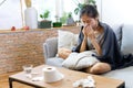 Sick Asian young woman sneeze at home on the sofa with a cold. Royalty Free Stock Photo