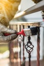 Covering forged railings by primer and paint, brush tool, rotection against rust, workflow, sun flare Royalty Free Stock Photo