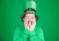 Covering his face with hands with delight. Happy Irish man with beard wearing green. Hipster in leprechaun hat and