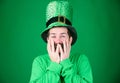 Covering his face with hands with delight. Happy Irish man with beard wearing green. Hipster in leprechaun hat and