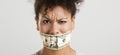 Covering mouth with a dollar banknote