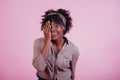 Covering right eye with hand. Attractive afro american woman in casual clothes at pink background in the studio Royalty Free Stock Photo