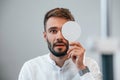 Covering right eye. Man is checking his vision indoors in the clinic Royalty Free Stock Photo